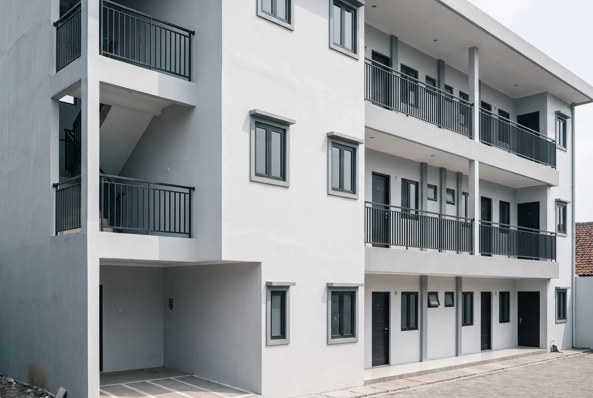 Bangunan kost tiga lantai dengan deretan kamar seragam dan koridor terbuka